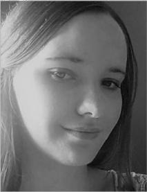 Portret kobiety z długimi włosami, uśmiechniętej, w czerni i bieli, z delikatnym oświetleniem z lewej strony twarzy.