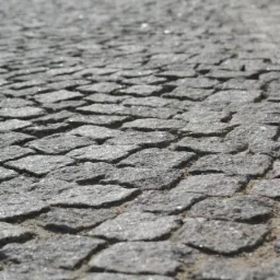 Szara kostka granitowa ułożona w regularny wzór, widok z niskiej perspektywy z rozmytym tłem.