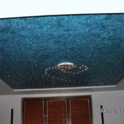 Błękitny sufit z efektem gwiezdnego nieba i nowoczesnym żyrandolem, widok z dołu na tle okna z żaluzjami.