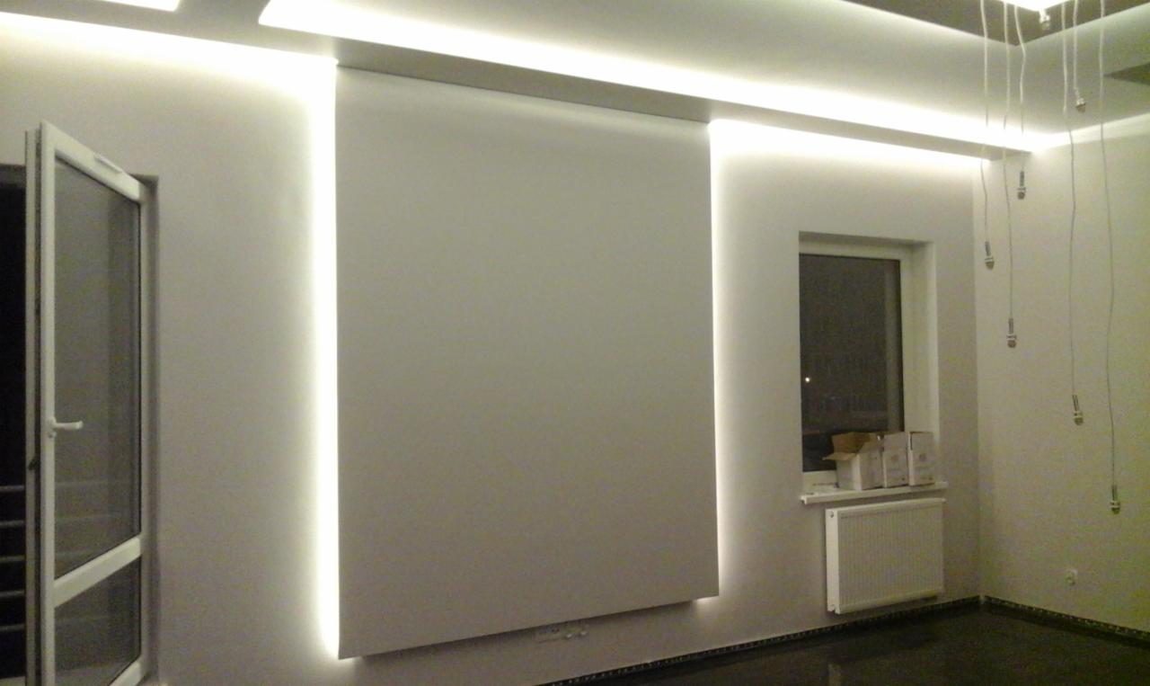 Nowoczesne wnętrze z oświetleniem LED wzdłuż ścian i sufitu, minimalistyczna roleta, otwarte drzwi balkonowe i okno z grzejnikiem.