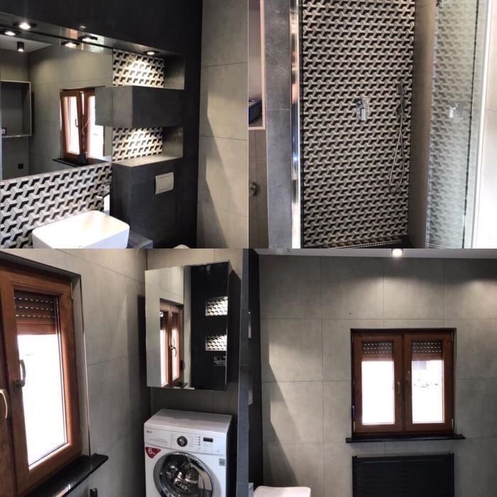 Nowoczesna łazienka z szarymi płytkami, kabiną prysznicową z geometrycznym wzorem, pralką pod oknem i drewnianą stolarką okienną.