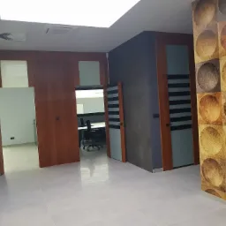 Nowoczesne biuro po remoncie: jasna podłoga z płytek, drewniane drzwi z przeszkleniami w czarne paski, szara ściana i ściana z dekoracyjną tapetą w geometryczne wzory kół.