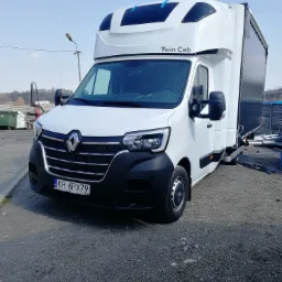 Biały Renault Master Twin Cab z czarną zabudową kontenerową, zaparkowany na szarym żwirowym podłożu, widoczny numer rejestracyjny KR 6PX79.