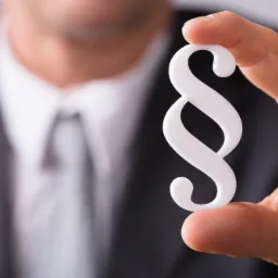 Mężczyzna w garniturze trzyma biały symbol paragrafu, wykonany z tworzywa, na tle rozmytego krawata i koszuli.