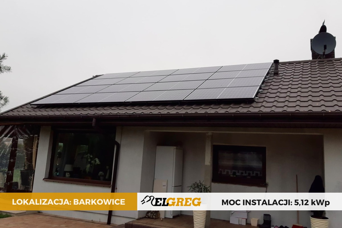 Panele słoneczne zamontowane na brązowym dachu domu jednorodzinnego w Barkowicach, widoczny komin z anteną satelitarną.