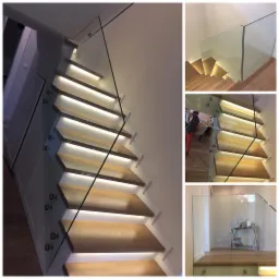 Schody drewniane z podświetleniem LED i szklaną balustradą, mocowaną punktowo, widok z dołu, fragment wnętrza z osobą w tle.