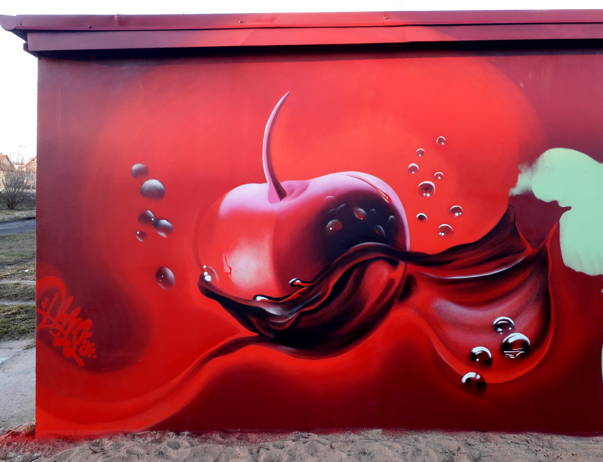 Czerwona ściana z namalowaną wiśnią i kroplami, graffiti w stylu realistycznym z podpisem autora w lewym dolnym rogu.