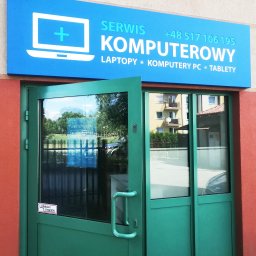 GRUPA BS - Serwis komputerów, laptopów i tabletów - Wejście do serwisu komputerowego w Krakowie z niebieskim szyldem z białym logo laptopa z plusem i napisem 'SERWIS KOMPUTEROWY LAPTOPY * KOMPUTERY PC * TABLETY' oraz numerem telefonu, zielone drzwi...