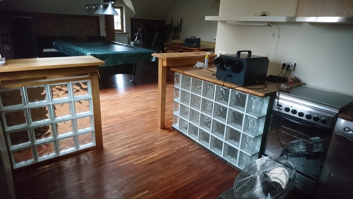 Ozonator przemysłowy na drewnianym blacie obok kuchenki, w tle stół bilardowy i drewniana podłoga.