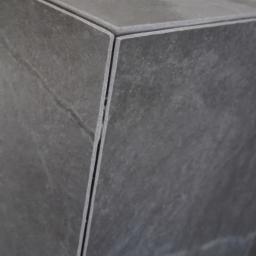 SzymańscybudPL - Szczegółowy widok narożnika obłożonego szarą płytką ceramiczną, z widoczną fugą i delikatną fakturą kamienia.