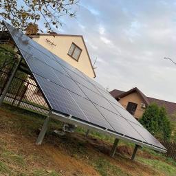 MILTON-PV - Instalacja paneli słonecznych na gruncie, widoczne wsporniki montażowe, w tle dom jednorodzinny i pochmurne niebo.