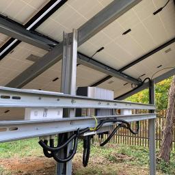 MILTON-PV - Montaż konstrukcji wsporczej paneli słonecznych w Mielcu, widok od spodu, z widocznymi przewodami i elementami mocującymi na tle zieleni.