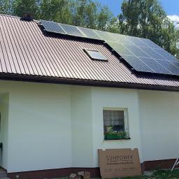 MILTON-PV - Brązowy dach z blachy trapezowej z zamontowanymi panelami słonecznymi; na ziemi kartonowe opakowanie paneli SunPower, w tle drzewa i rusztowanie.