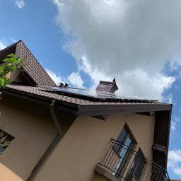 MILTON-PV - Instalacja paneli fotowoltaicznych na brązowym dachu domu jednorodzinnego z widocznym kominem i błękitnym niebem z chmurami.