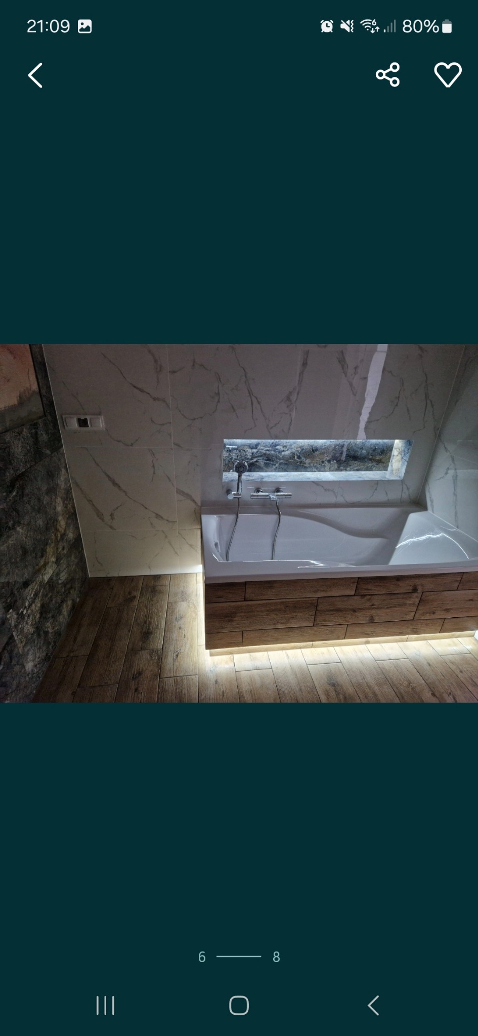 Nowoczesna łazienka z wanną obudowaną drewnem, podświetleniem LED i marmurowymi płytkami na ścianach, widok z góry.