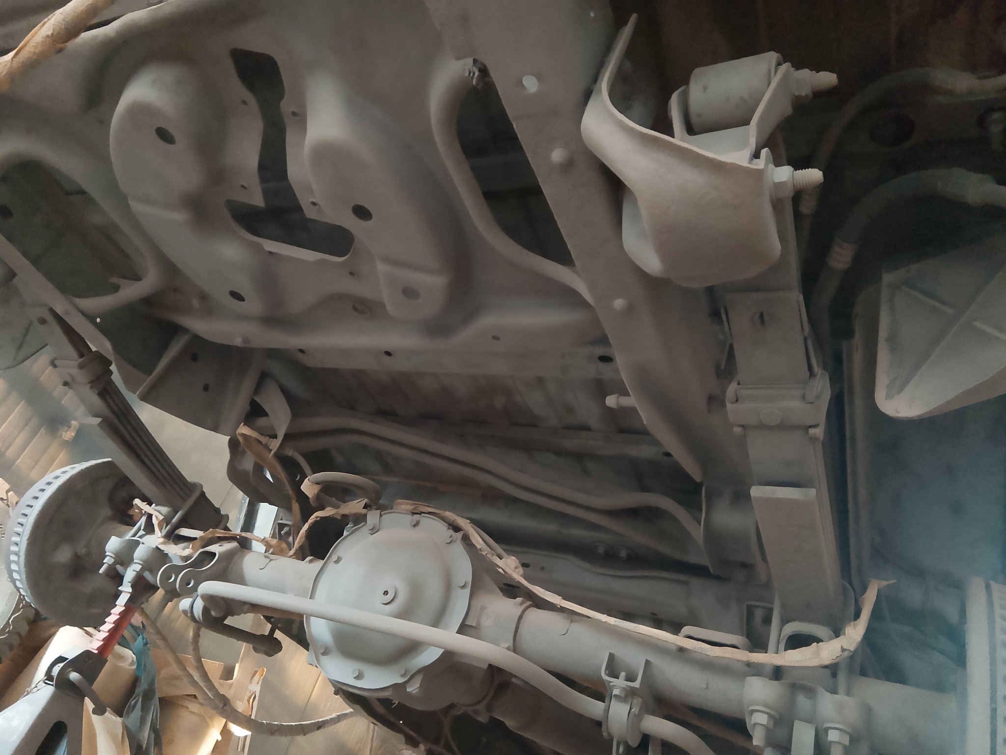 Podwozie samochodu po piaskowaniu, widoczne elementy zawieszenia i układu napędowego pokryte jednolitą warstwą zabezpieczającą. Ujęcie od dołu, eksponuje detale konstrukcyjne.