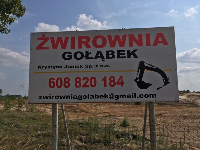 Billboard reklamowy z napisem 'Żwirownia Gołąbek', danymi kontaktowymi i grafiką koparki na tle wyrobiska.