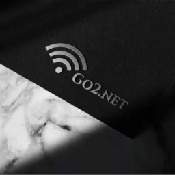 Eleganckie logo firmy GO2.NET w srebrnym kolorze, przedstawiające symbol Wi-Fi, umieszczone na czarnym, teksturowanym tle z marmurowym akcentem u dołu.