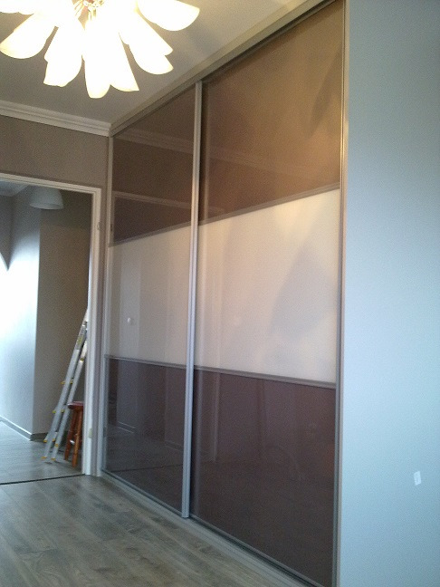 Wnętrze z przesuwną szafą z trzema panelami: brązowy, biały i brązowy, widoczna drabina w tle.