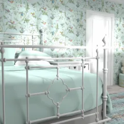 Pokój dziecięcy z białym metalowym łóżkiem, turkusową pościelą, tapetą w ptaki i kwiaty, oraz pufą z pluszowym misiem