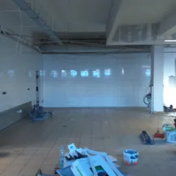 Wnętrze remontowanego pomieszczenia z białymi płytkami na ścianach, widoczne narzędzia, paleta z wodą, poziomica oparta o filar i dwóch mężczyzn w tle.