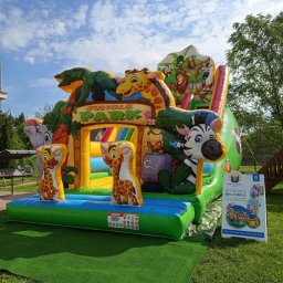 Zbigniew Paprocki - Kolorowy, dmuchany plac zabaw 'Jungle Park' z motywami zwierzęcymi, ustawiony na trawie. Widoczny baner reklamowy z ofertą wynajmu dmuchańców.