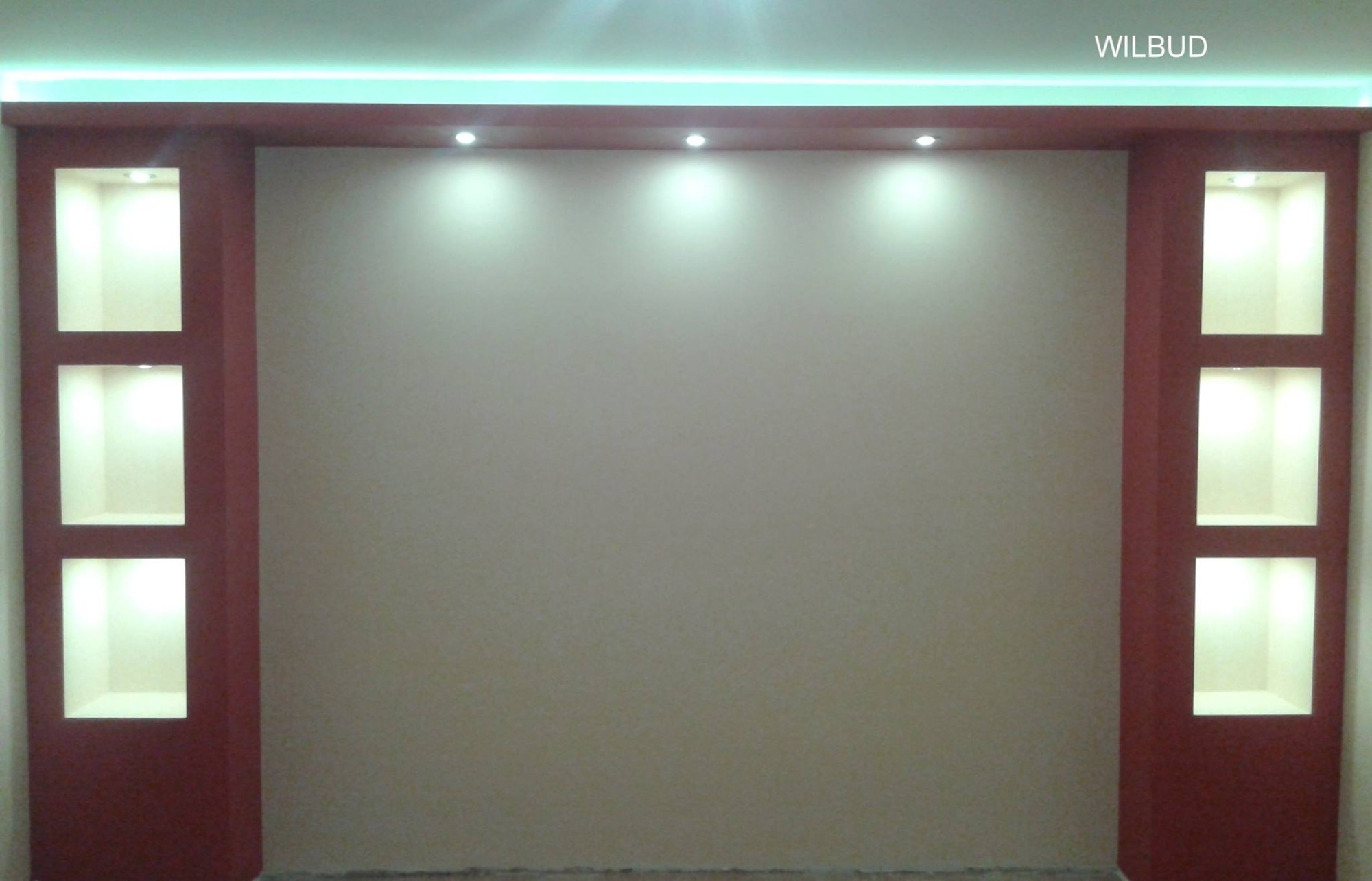 Ściana z gładzią, oświetleniem LED podsufitowym i wnękami po bokach, pomalowanymi na bordowo z wewnętrznym oświetleniem punktowym.