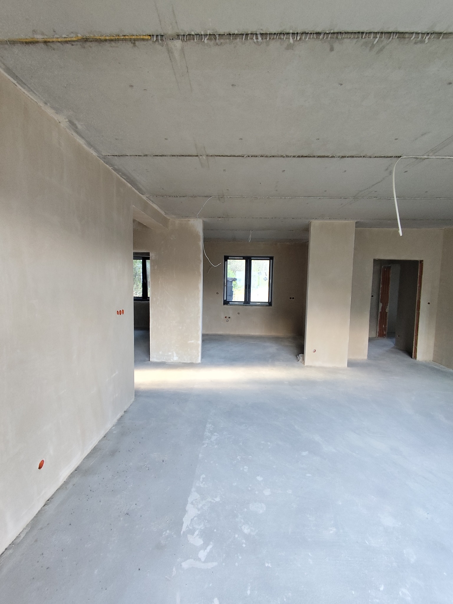 Wnętrze po tynkowaniu maszynowym w Tarnowskich Górach. Widoczne gładkie ściany i sufit, przygotowane do dalszych prac wykończeniowych. Surowy stan.