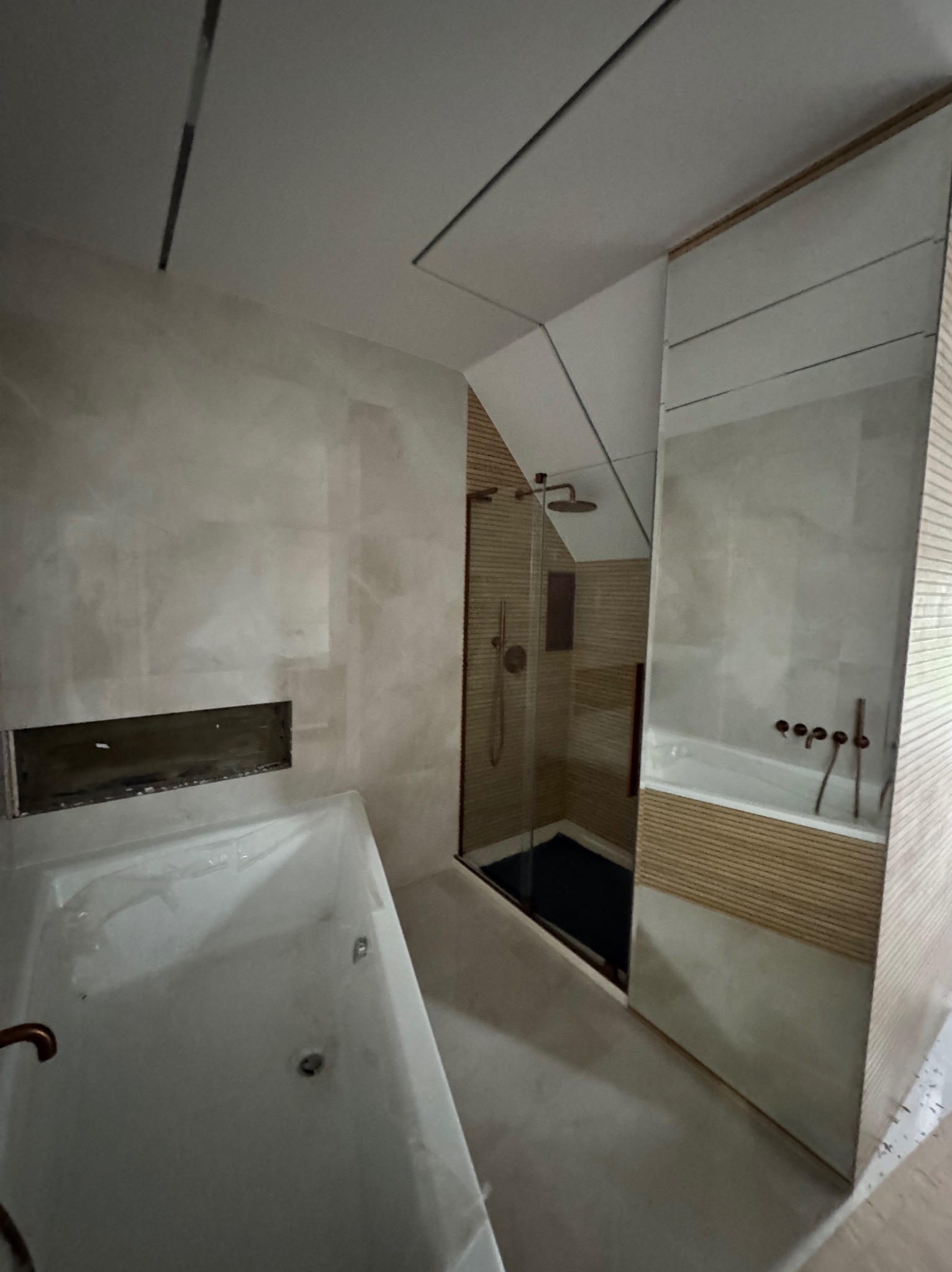 Nowoczesna łazienka po remoncie: beżowe płytki, kabina prysznicowa typu walk-in, wanna z hydromasażem, minimalistyczna armatura, oświetlenie ledowe i lustra.