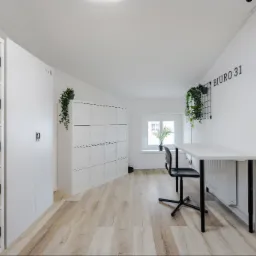 Nowoczesne wirtualne biuro z białymi szafkami z elektronicznymi zamkami numerowanymi od 29 do 50, biurkiem z czarnym krzesłem, roślinami doniczkowymi i motywującymi plakatami na ścianie z napisem...