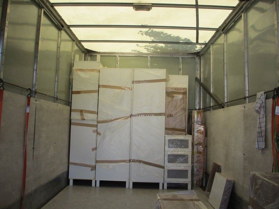 Wnętrze paki busa z zabezpieczonymi meblami oklejonymi taśmą i folią, przygotowanymi do transportu.