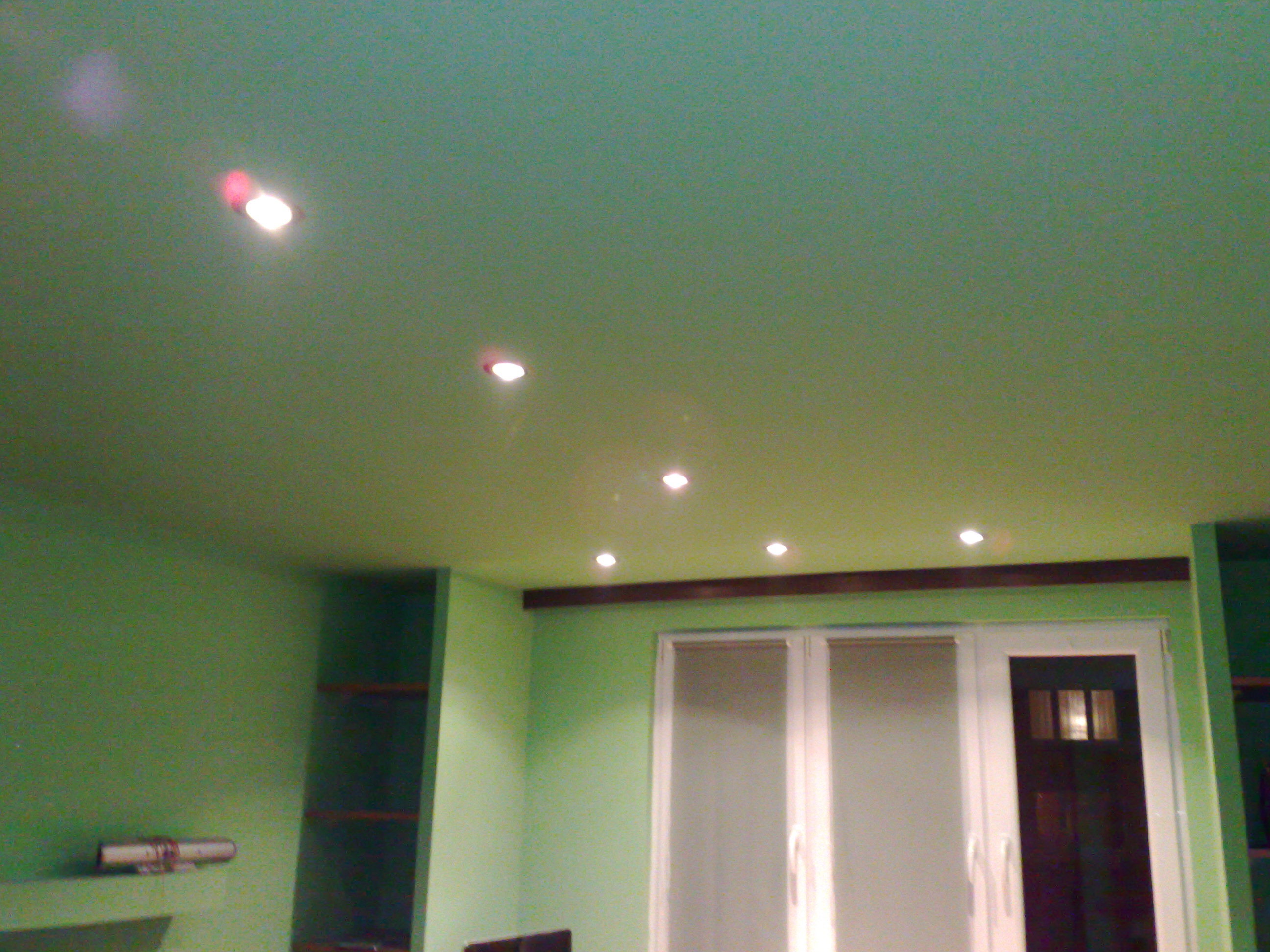 Zielone wnętrze po remoncie z zamontowanymi punktowymi lampami sufitowymi i nowymi oknami balkonowymi.