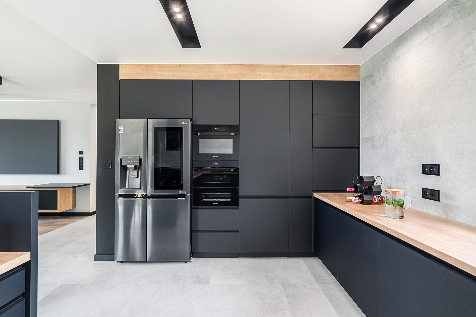 Nowoczesna kuchnia w Tomaszowie Mazowieckim z zabudową w kolorze grafitu, drewnianym blatem i srebrną lodówką side-by-side.