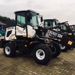 Rząd nowych, białych i czarnych maszyn budowlanych Kingway SZM z białymi felgami, stojących na brukowanym placu, widocznych z boku.