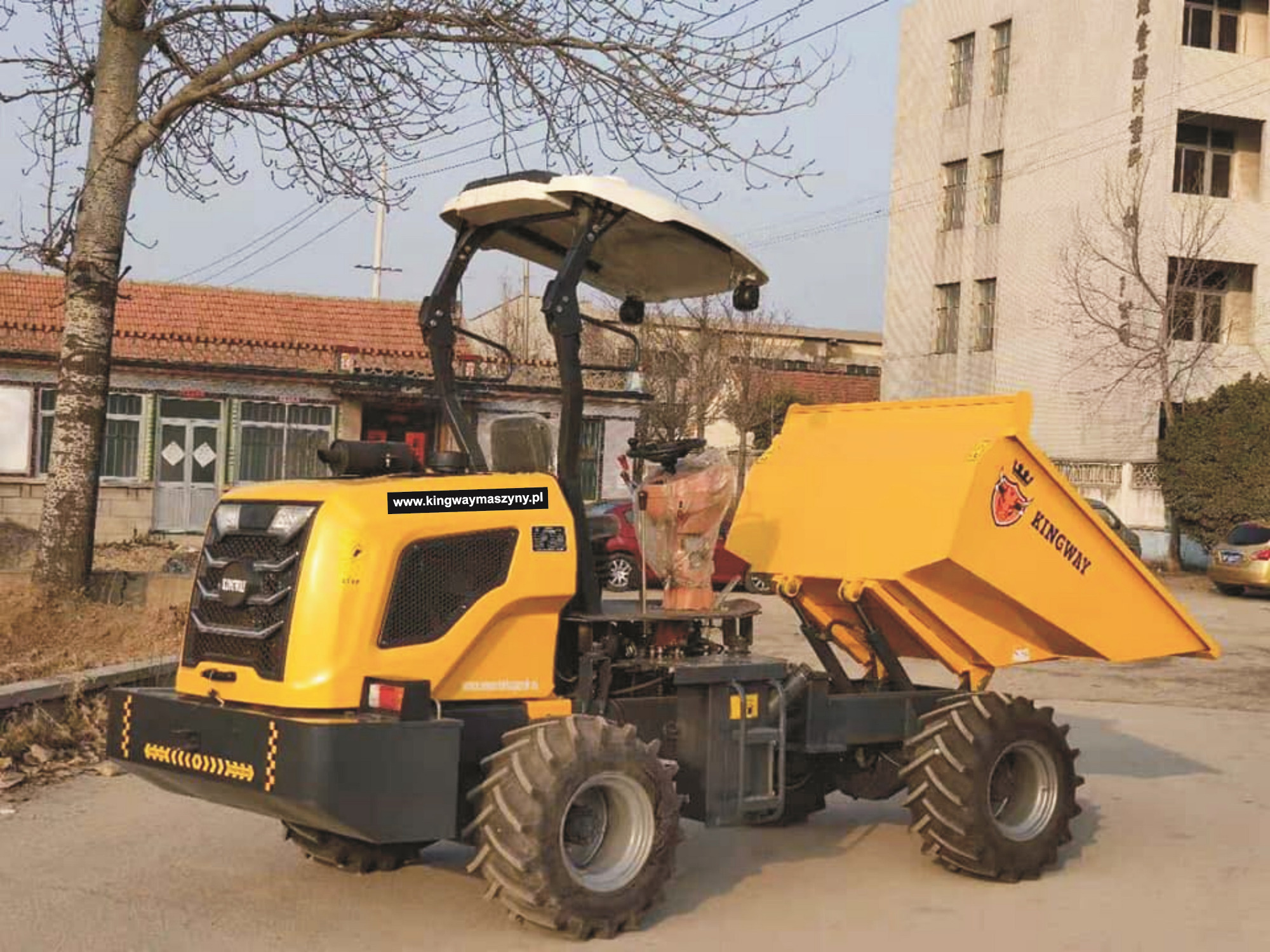Żółta, przegubowa wywrotka budowlana marki Kingway z podniesioną skrzynią ładunkową, na tle budynku i drzewa.