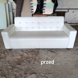 Havia Bartosz Pawlak - Biała, skórzana sofa z pikowanym oparciem i kryształkami, stojąca na betonowej podłodze w warsztacie tapicerskim, z widocznymi materiałami tapicerskimi w tle. Na podłodze widoczny napis 'przed'.