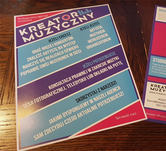 Ulotka reklamowa agencji muzycznej Kreator Muzyczny z ofertą dla artystów, muzyków, menedżerów i organizatorów wydarzeń muzycznych, leżąca na drewnianym stole.
