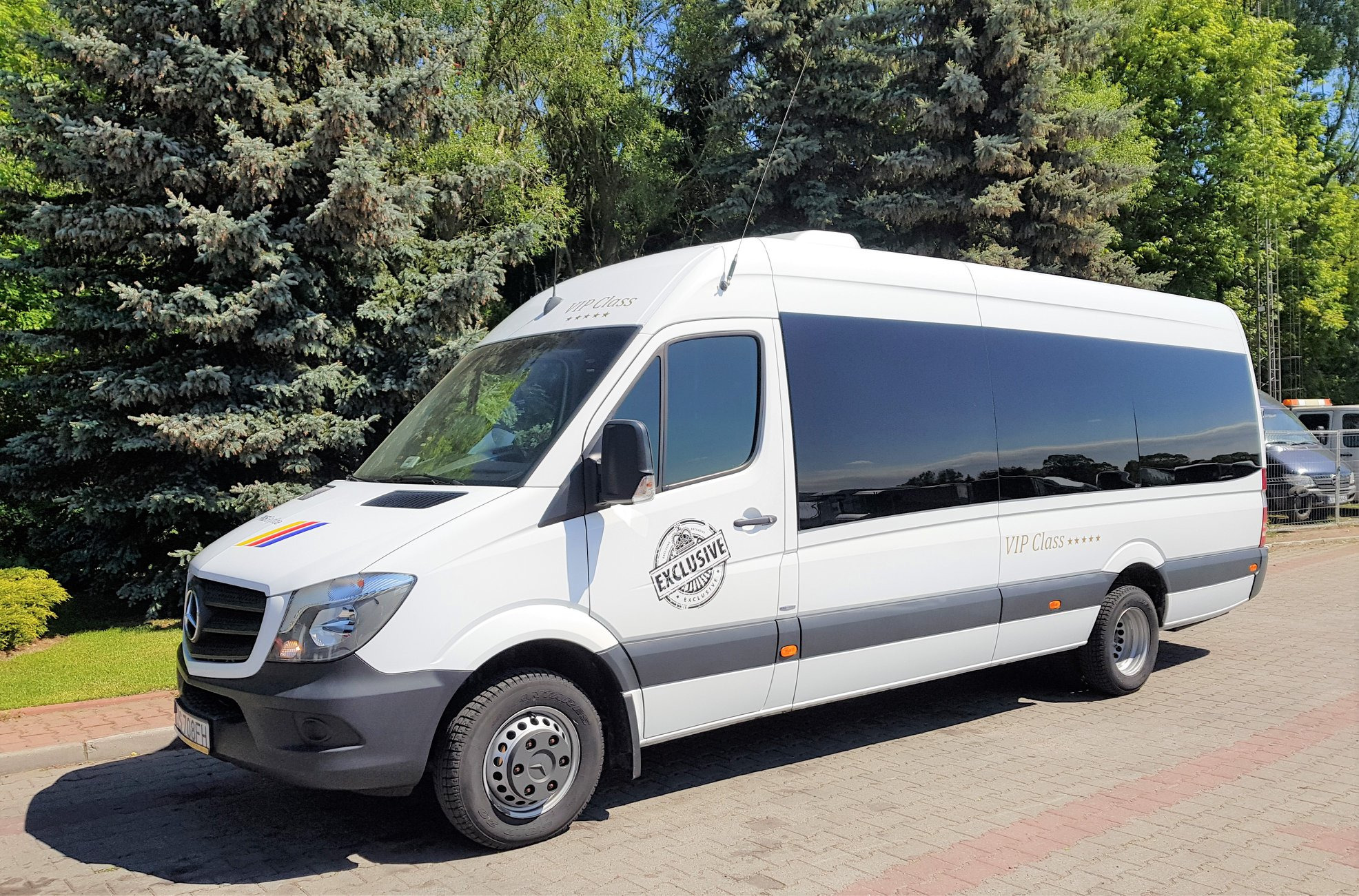Biały bus Mercedes Sprinter z napisem 'VIP Class' i logo 'Exclusive' na tle zieleni.