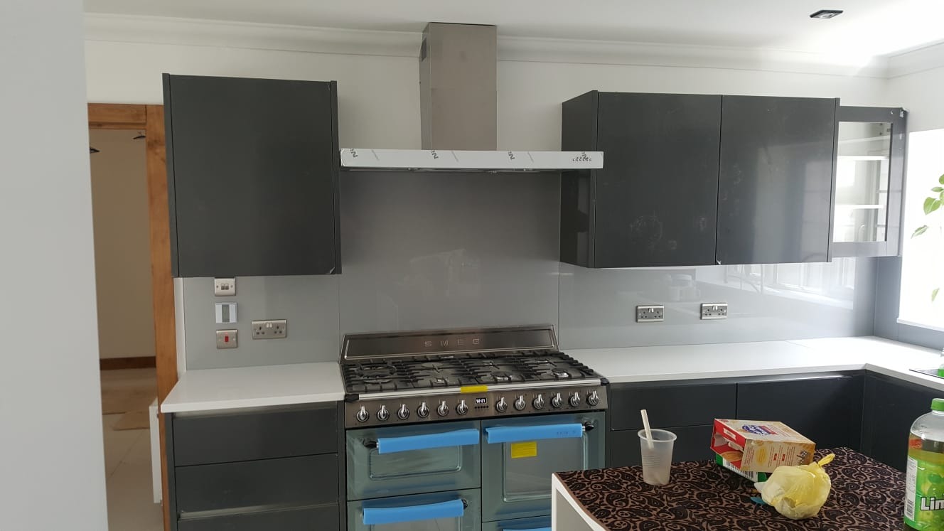 Nowoczesna kuchnia w WD244LL z szarymi szafkami, białym blatem i stalową kuchenką Smeg z niebieską folią ochronną, oczekująca na wykończenie.