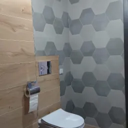 Nowoczesna toaleta podwieszana w łazience z drewnopodobnymi płytkami i heksagonalnymi szarymi płytkami na ścianie