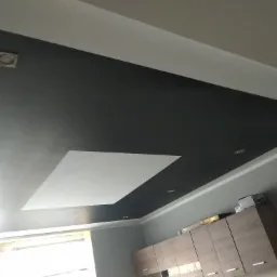 Dwukolorowy sufit podwieszany z wbudowanym oświetleniem punktowym, widok z dołu na tle szafek kuchennych.