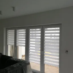 Trzyczęściowe okno PCV z zamontowanymi roletami dzień noc, widok z wnętrza, meble przykryte folią ochronną