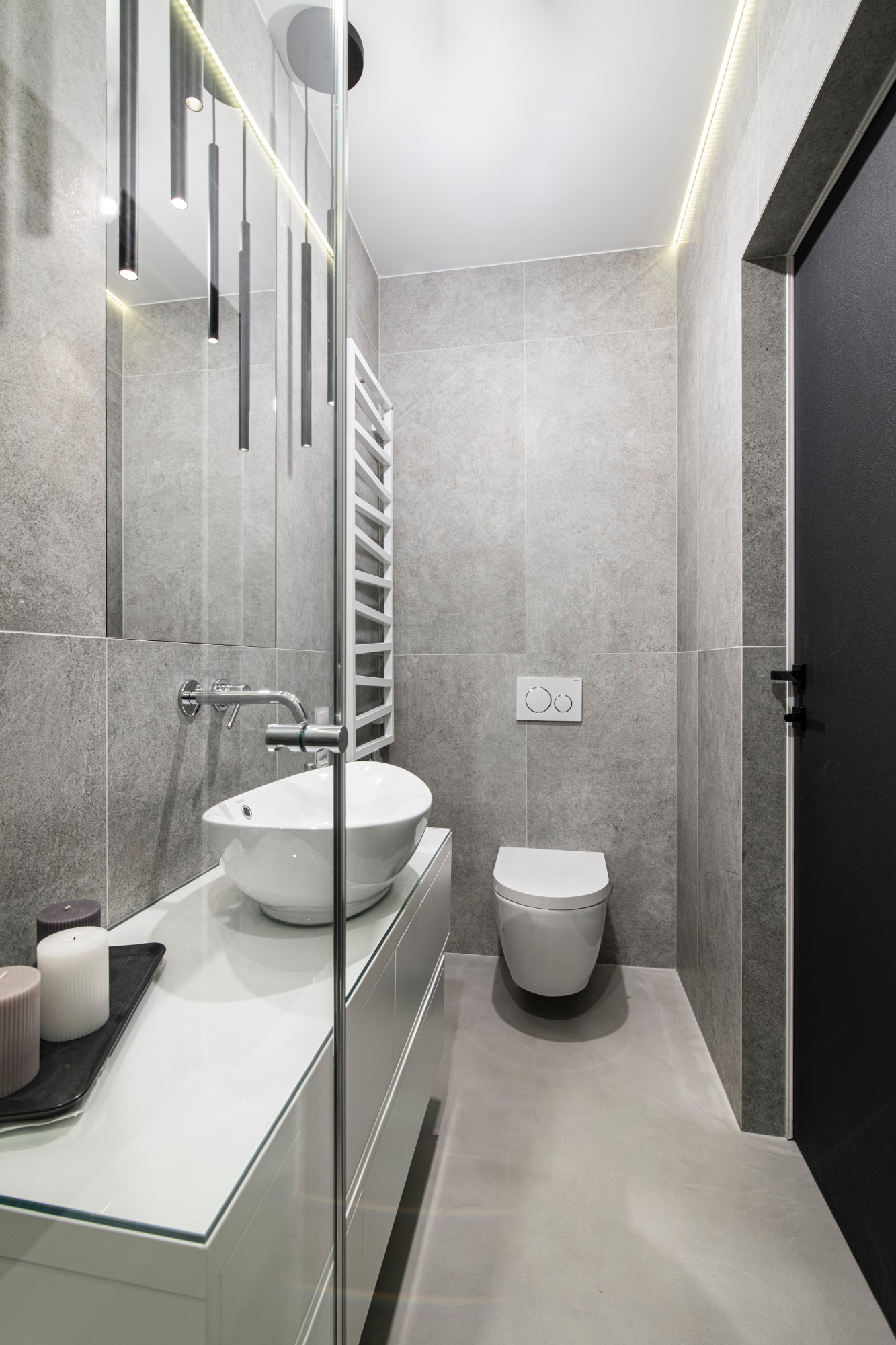 Nowoczesna łazienka w odcieniach szarości z białą umywalką nablatową, podświetlanym lustrem i czarnymi akcentami, minimalistyczny design