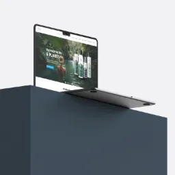 Laptop wyświetla stronę internetową z motywem naturalnych kosmetyków, na tle minimalistycznego, szarego bloku.