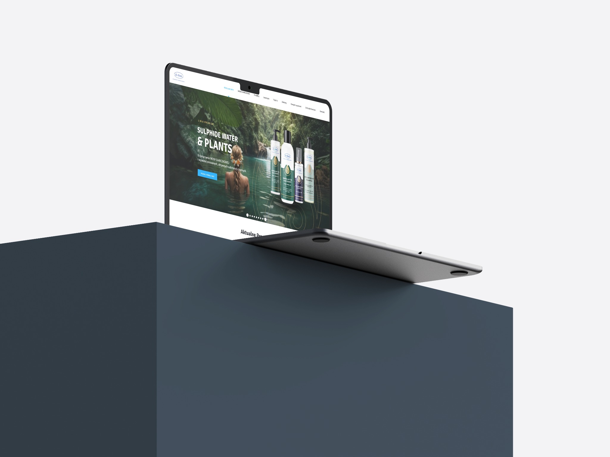 Laptop wyświetla stronę internetową z motywem naturalnych kosmetyków, na tle minimalistycznego, szarego bloku.