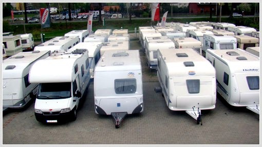 Plac z dużą liczbą zaparkowanych przyczep kempingowych i kamperów różnych marek, widoczny z góry.