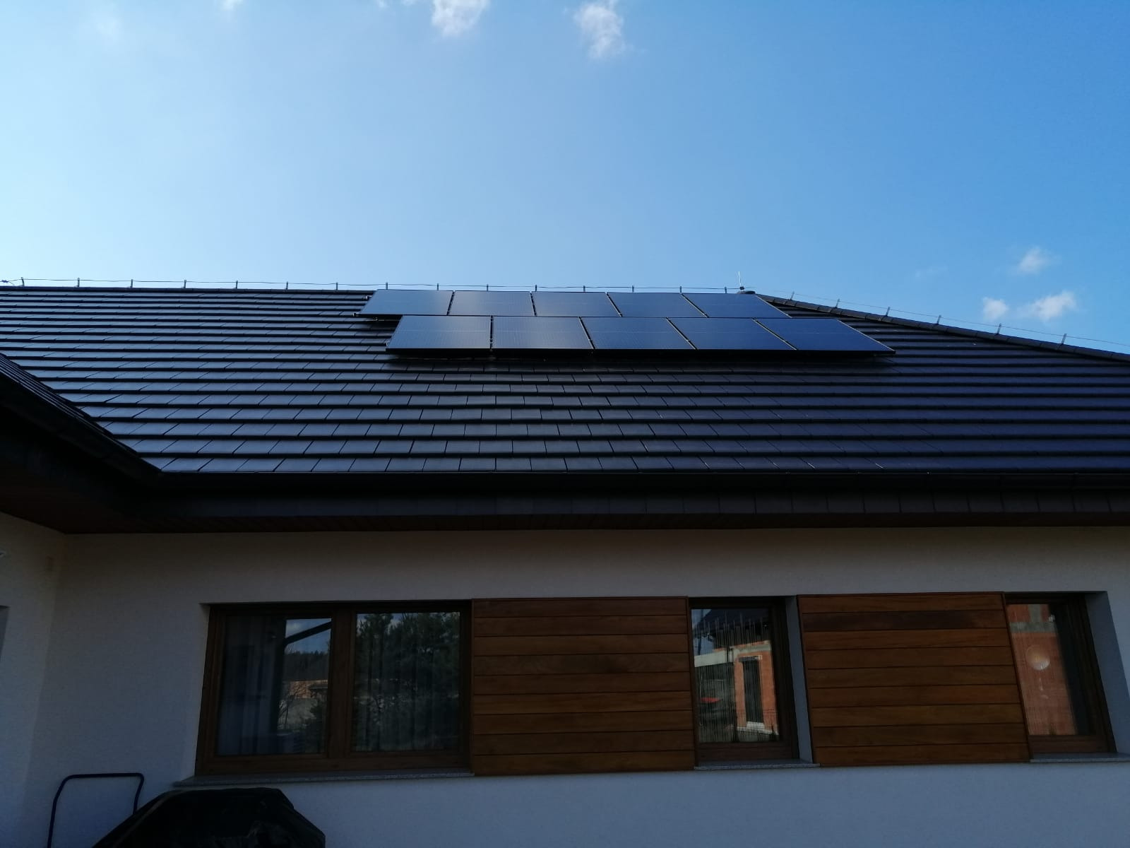 Panel słoneczny Bauer FB 330Wp na dachu domu z dachówką ceramiczną, falownik SolarEdge SE 9K, błękitne niebo w tle.