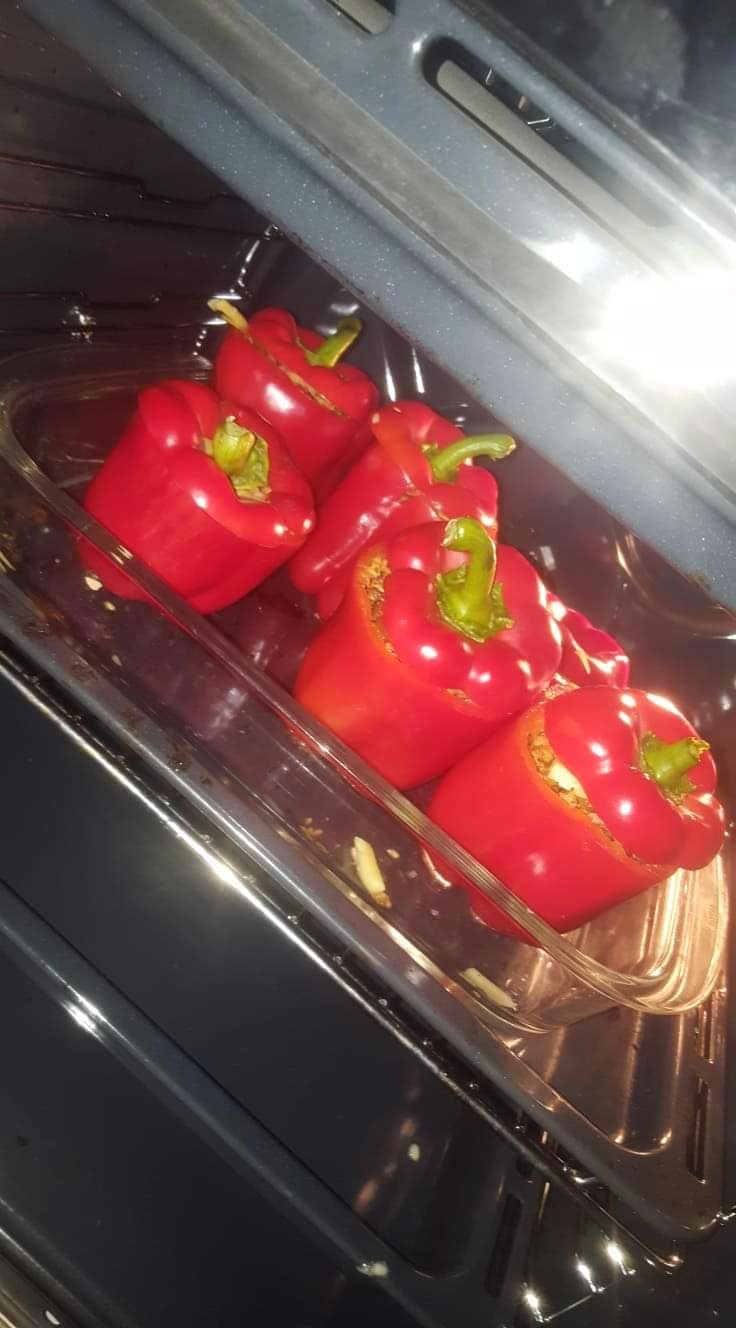 Czerwone papryki faszerowane w szklanym naczyniu, pieczone w piekarniku.
