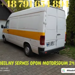 Biały bus z żółtym pasem, zaparkowany na kostce brukowej, z widocznym numerem telefonu i napisem 'Mobilny Serwis Opon', tablica rejestracyjna WP1 6079C.