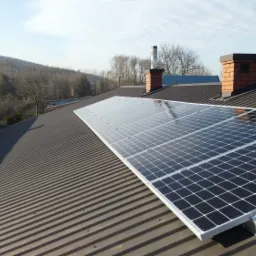 Panel słoneczny SELFA 320 W HC o mocy 3,52 kWp zamontowany na metalowym dachu domu w Nowej Słupi, z kominem w tle.